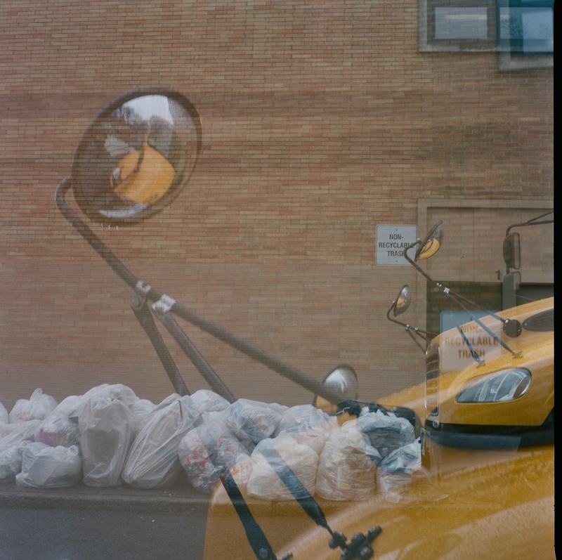 Trash piled up on a road by a school bus.