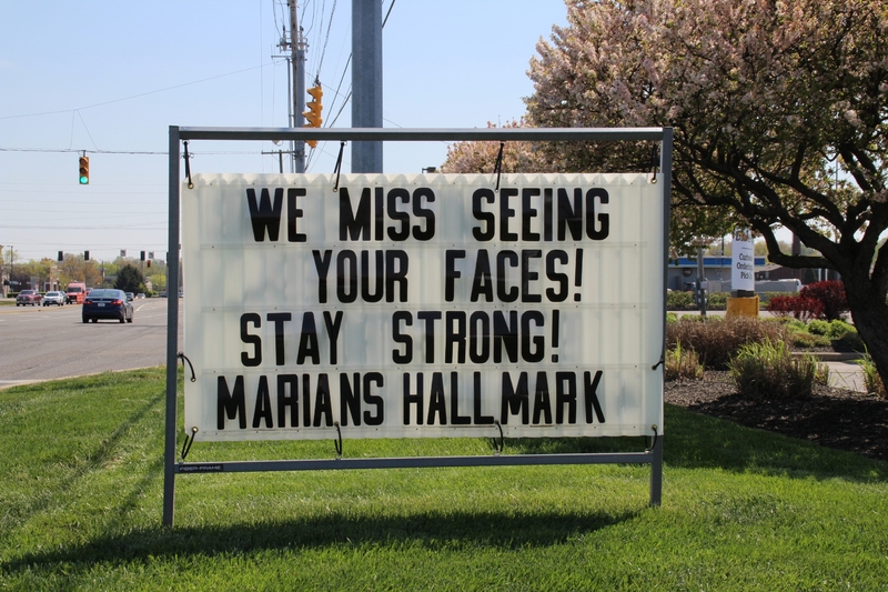 Sign reading "We miss seeing your faces! Stay Strong! Marians Hallmark".