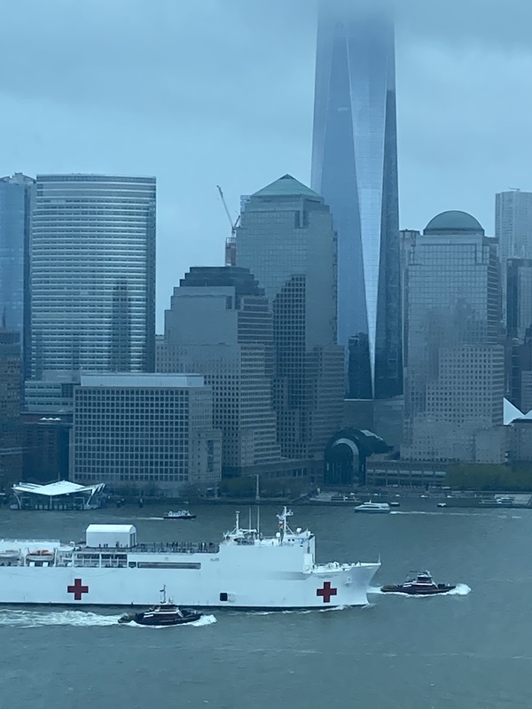 A large boat passing tall skyscrapers. 