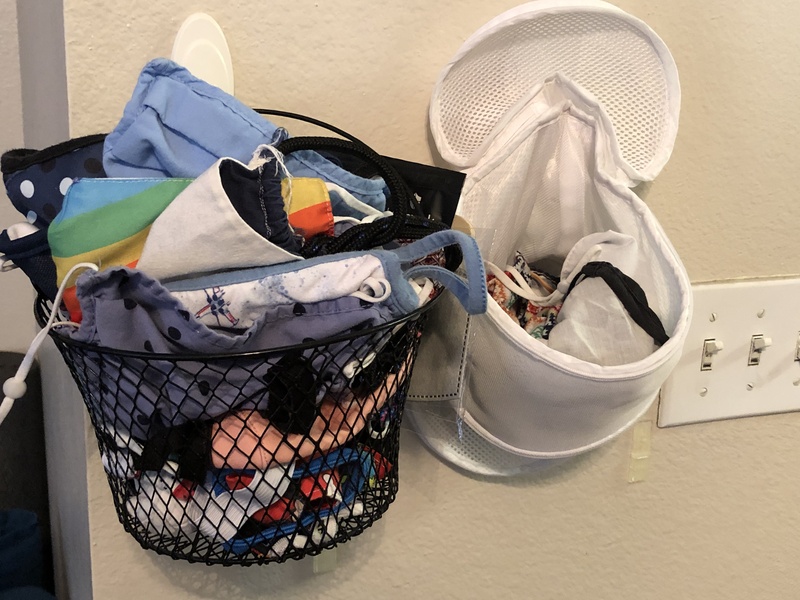 This is a picture of a collection of face masks being stored in several containers on a wall. 