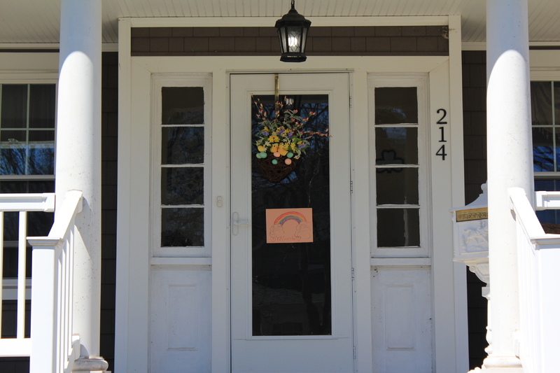 A residential house with a rainbow on the front screen door.