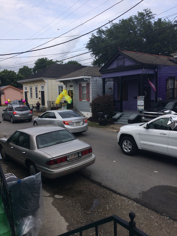 Image of cars driving by a house with balloons in front of it, for a pandemic style graduation party.