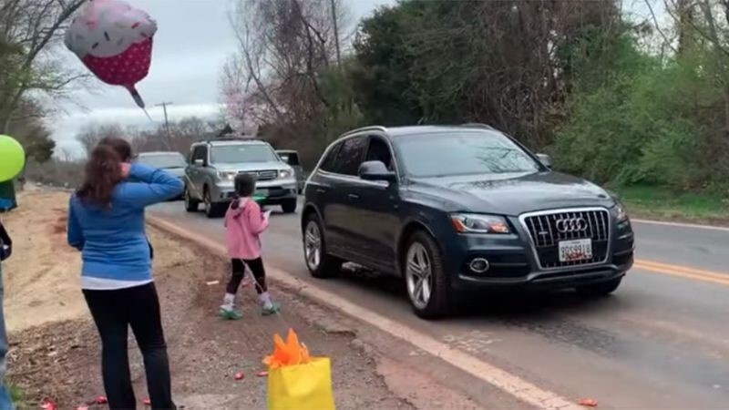 Cars driving by wishing a child a happy birthday.