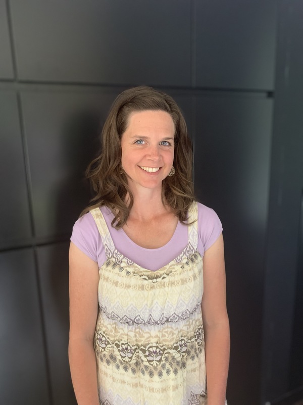 Photo of a woman smiling in front of a black background.