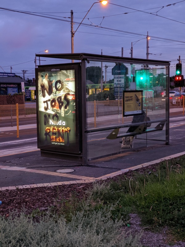 Spraypainted words on a bus stop. 