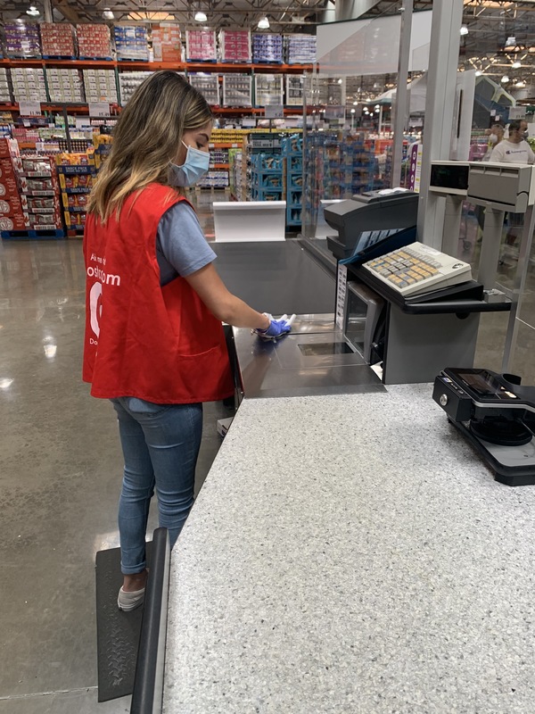 A person with a mask wiping down a register. 