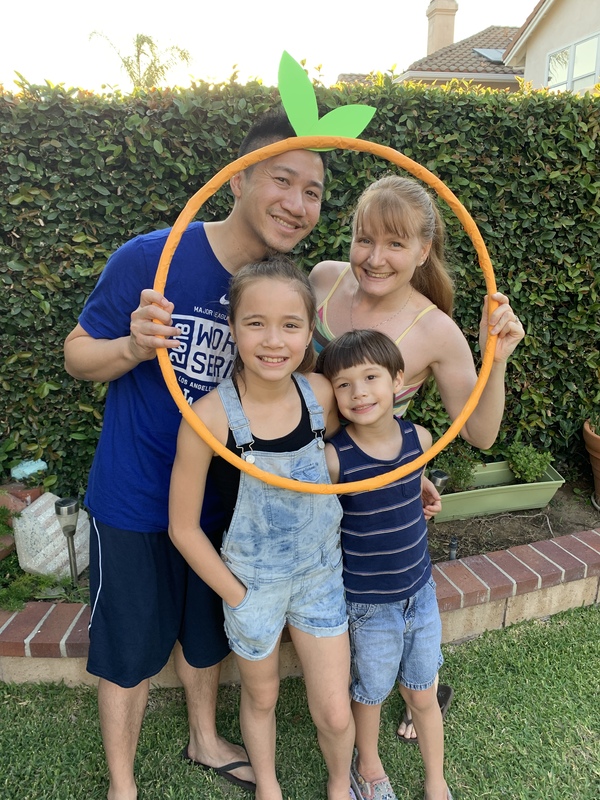 Two adults and two children holding an outline of a pumpkin. 