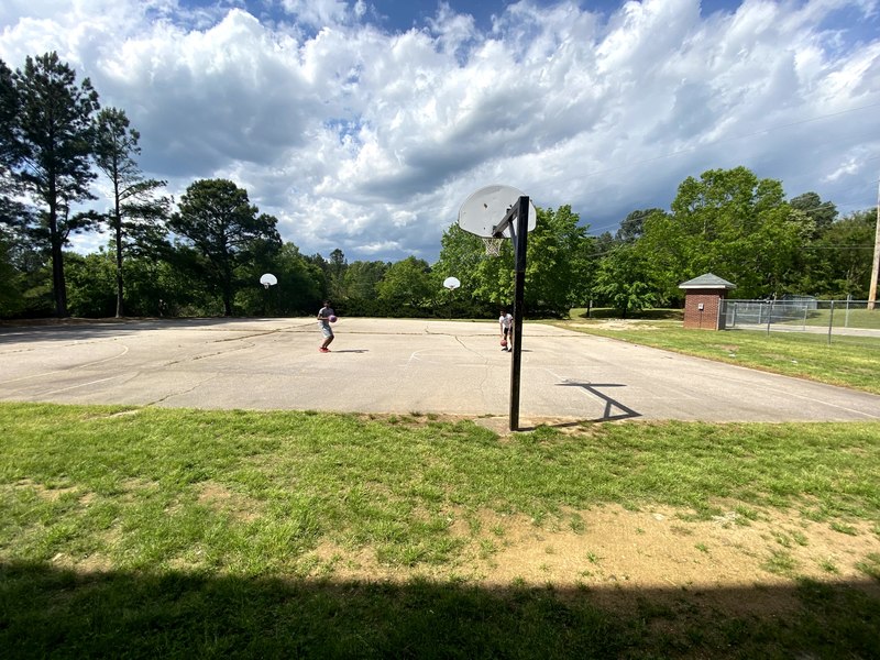 Two people at a basketball court outside.