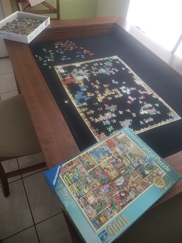 A table that has a puzzle being put together in progress. 