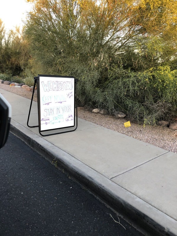 A whiteboard sign on the sidewalk.