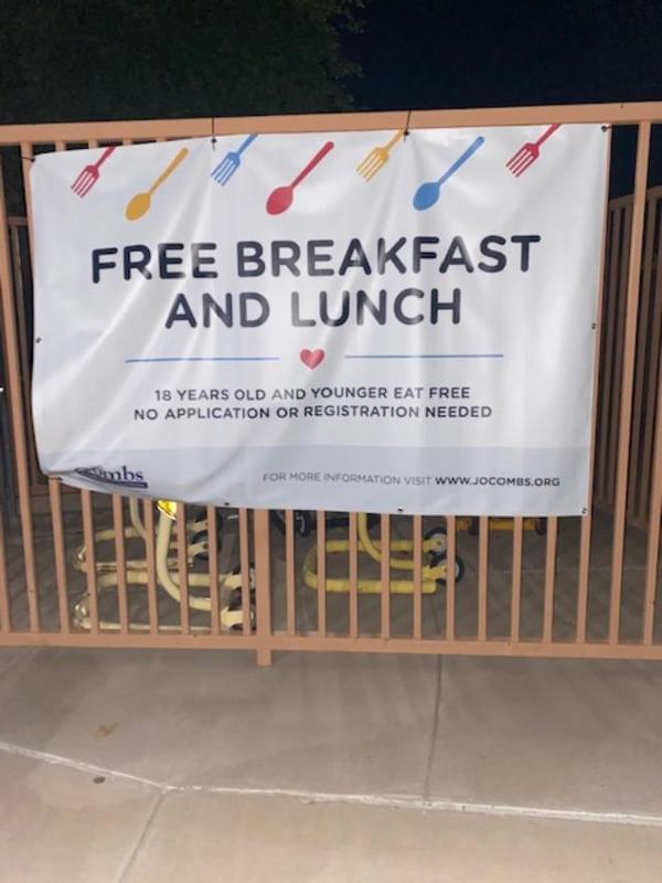 A sign with black writing on the side of a fence. 