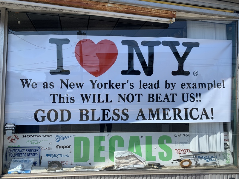 A white sign with black lettering on a glass window. 