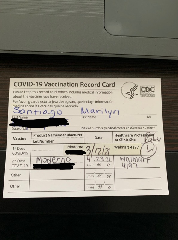 This is a picture taken of a person's vaccine card. Any personal information has been blurred out. 