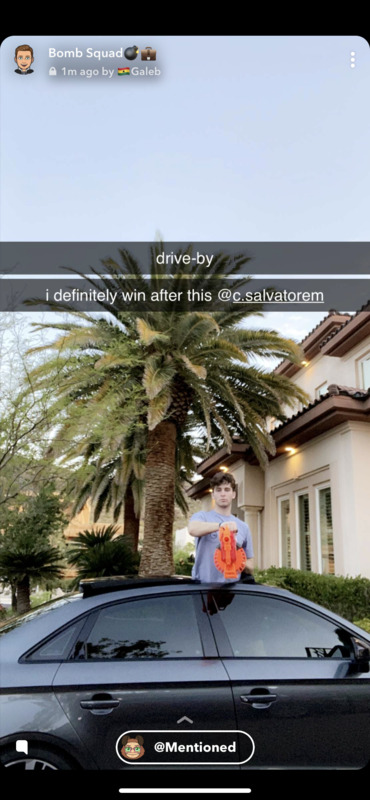 SnapChat screenshot. A boy stands next to a black car.