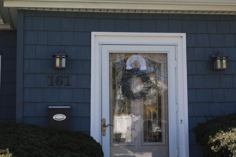 A residential house with a rainbow on the front screen door.