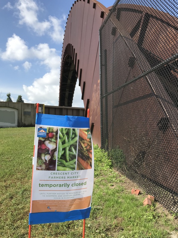 A sign that is stuck into the ground that says: Crescent City Farmers Market temporarily closed. 