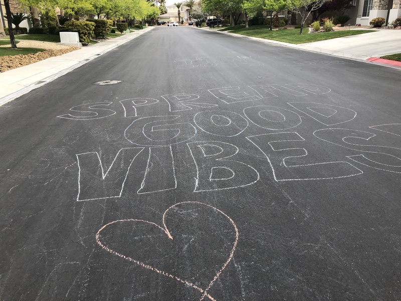 A street has chalk written on it that says: SPREAD GOOD VIBES.