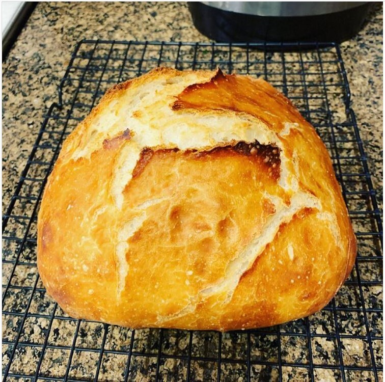 This is a close up picture of a freshly baked loaf of bread resting out on a kitchen counter. 