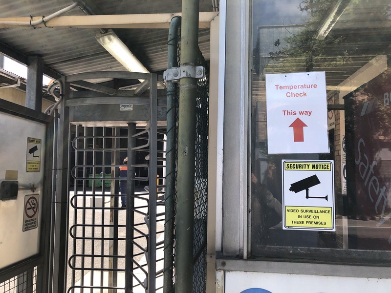 Picture at a sign at the entrance to a factory in Australia reading "Temperature check, this way". 