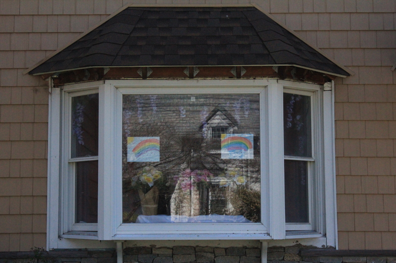 A residential house with two rainbows in the front window. 