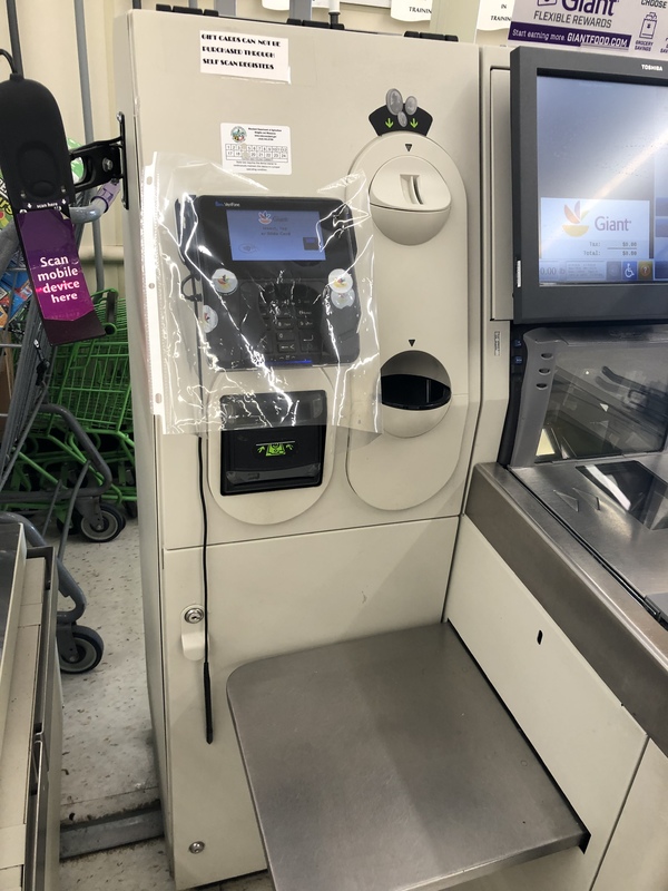 A self check out station at a grocery store with a plastic covering over the key pad.