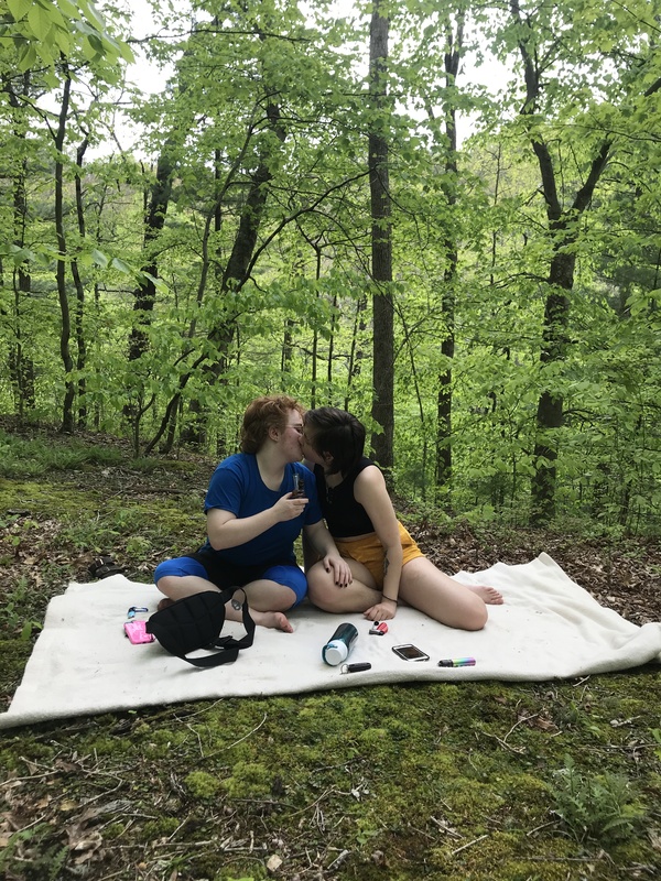 couple kissing on a picnic blanket in the woods