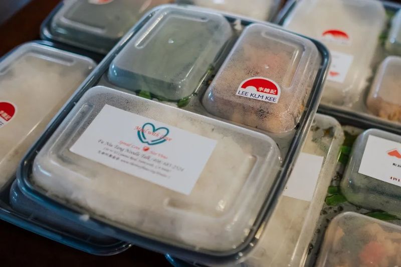 Many to-go boxes of lunches with "Made with Love" sticker