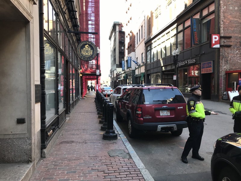 Two police officers standing on a street next to a sidewalk.