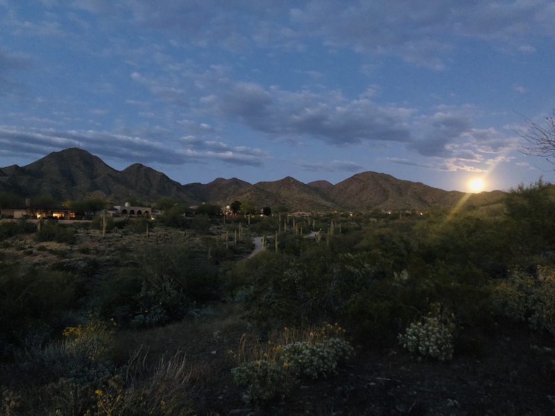 The moon rising near some mountains. 