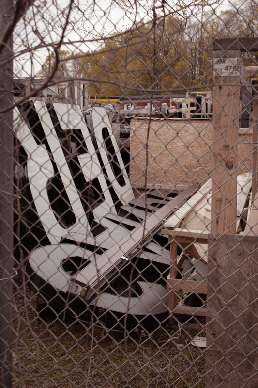 This is a picture of a pile of letters for a sign being stored behind a chain link fence. 