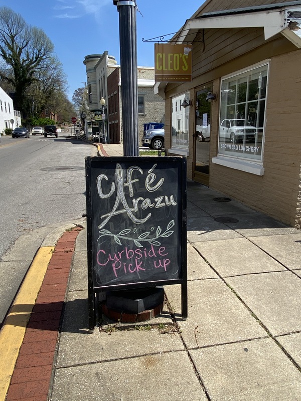 A chalkboard sign outside of a cafe reading "Curbside Pickup".