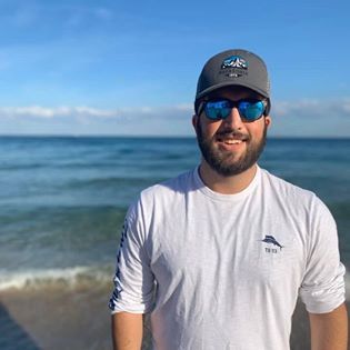 A person smiling standing in front of a beach. 