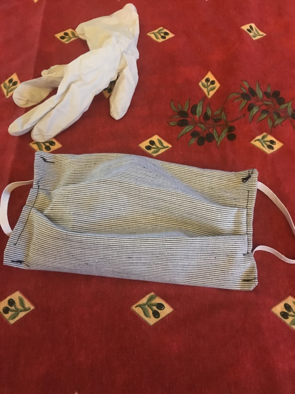 A cloth mask and a disposable glove is on top of a table. 