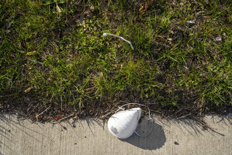 A facemask laying on the sidewalk. 