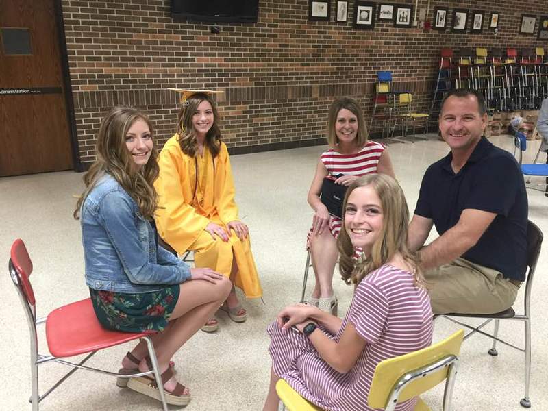 Image of a family sitting in a circle in chairs waiting for high school graduation to start. 