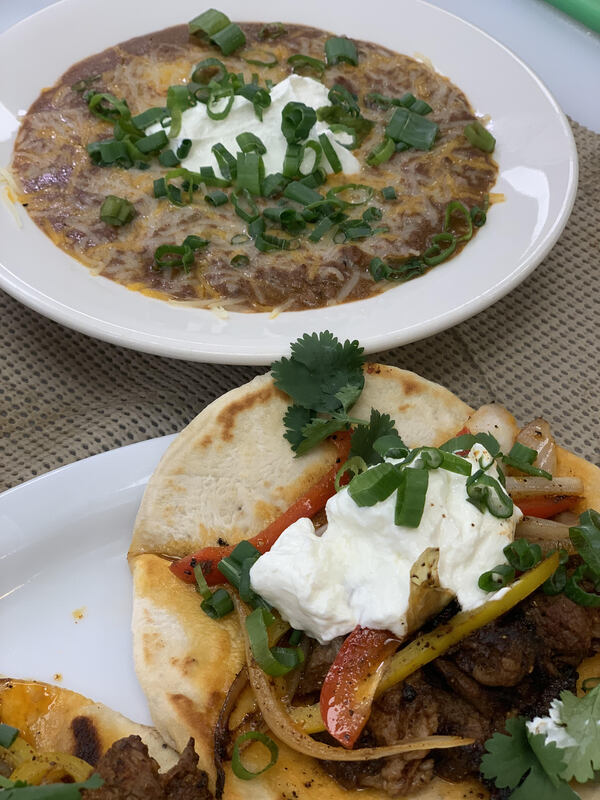 This is a picture of a bowl of soup and what seems to be a taco that is sitting on a table ready to eat. 