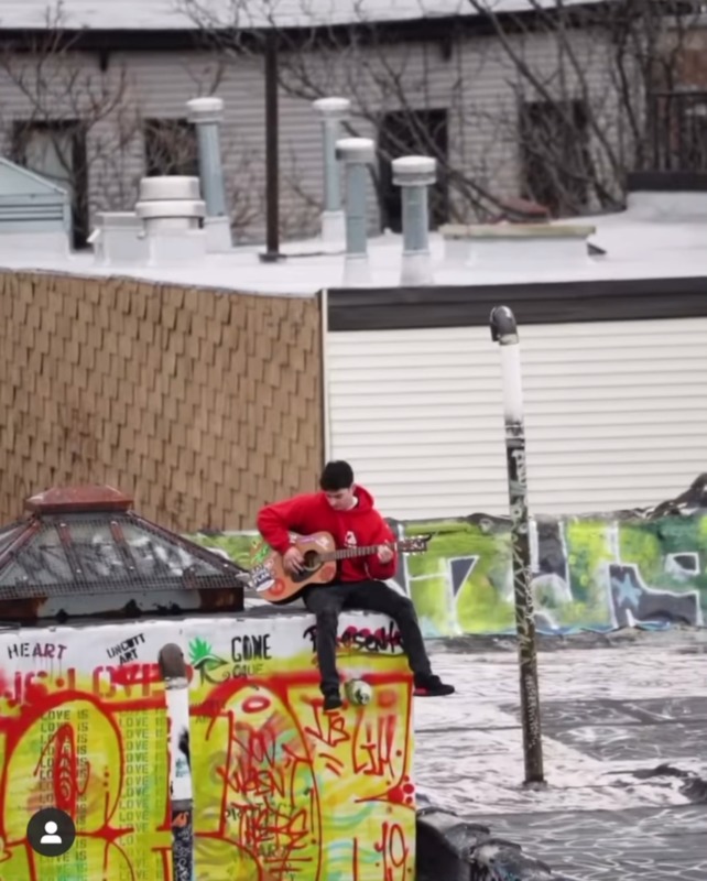 A person playing guitar on top of a building. 