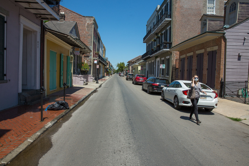 A masked person walking down an empty street.