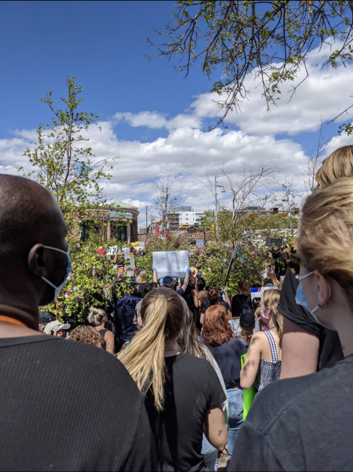 This is a picture of a group of face masked people attending a protest. 