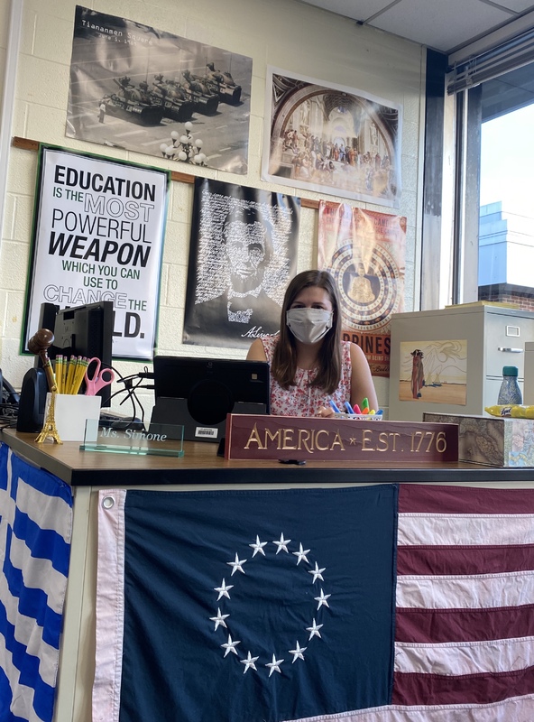 This is a picture taken of a teacher sitting at a desk.