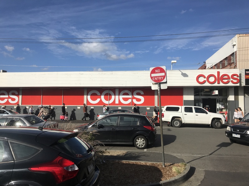 A line of people outside a supermarket. 