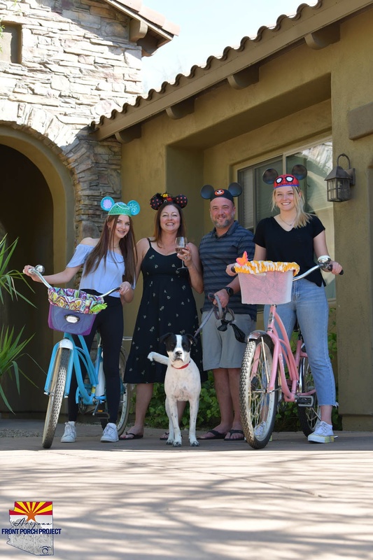 Four people posing for a picture, two with bikes and one holding a dog. 