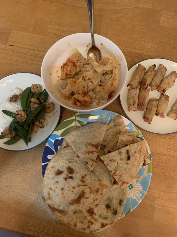 This is a picture taken of several plates full of different types of food laid out on a dining room table. 