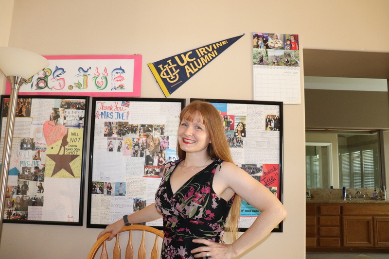 A woman standing in front of a wall decorated as a classroom background during distance learning.