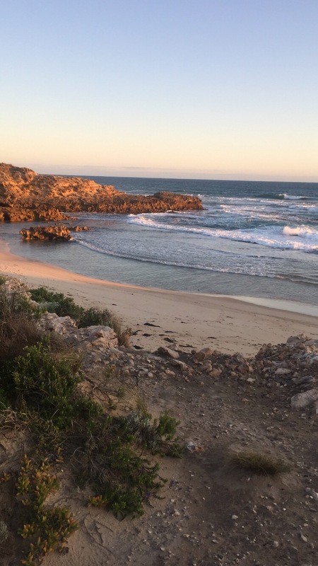 This is a picture of the ocean and a beach at sunset. 