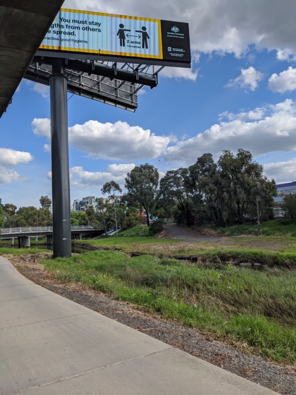 A billboard in front of trees and a blue sky. 