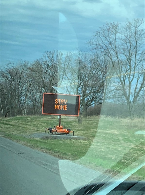 Image of a sign on the side of the highway which says stay home.