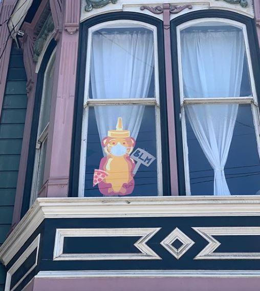 A photo of a sign in a window. The sign is of a honey bear with a BLM sign.