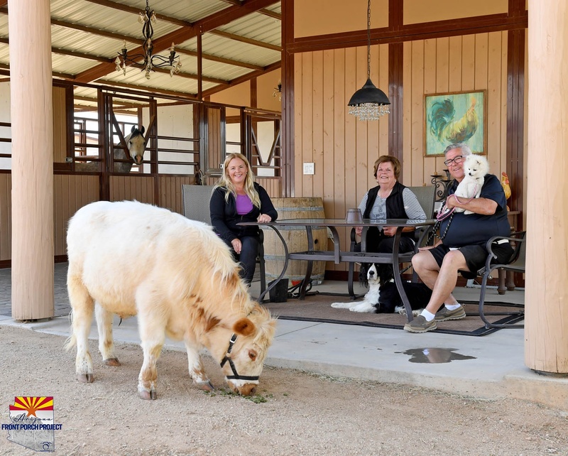 A calf eating in front of three people. 