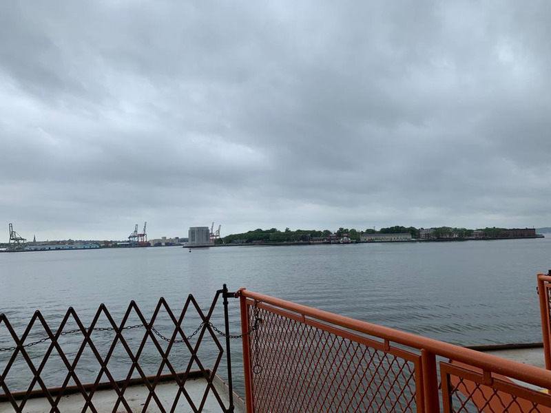 This is a picture taken from a pier, looking out onto a body of water with land visible on the other side.